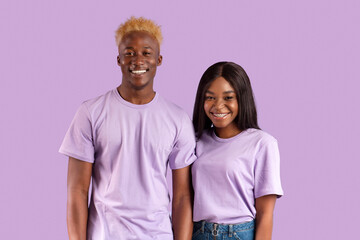 Obraz premium Positive African American couple smiling and looking at camera on violet studio background