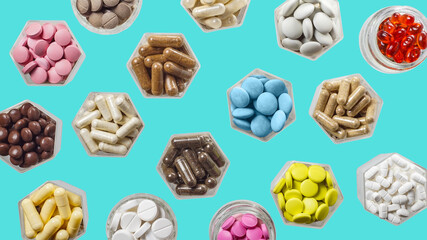 Medical capsules and pills in hexagonal jars on blue background