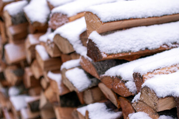 Snow covered firewood. Stack of wood cut. Snow on the timber stack. Wooden log store under snow.