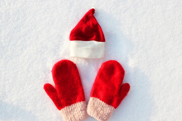Red Santa hat and knitted mittens lie on the snow. mitten lying on the snow in winter. Holiday Decorations Christmas and New Year Traditions Panoramic Banner Free Space Text Top View Flst lay
