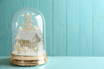 Beautiful snow globe on light blue wooden table, space for text