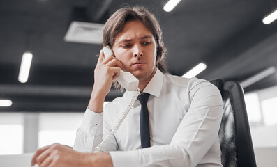 Serious businessman speaking on telephone in office