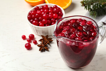 Fresh cranberry sauce in pitcher on white table, space for text