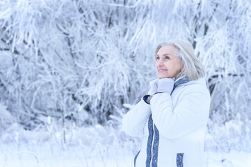 Fototapeta na wymiar Beautiful senior woman posing in snowy winter park