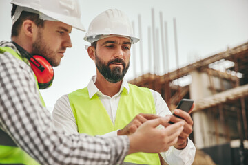 Architects working with smartphone on construction site
