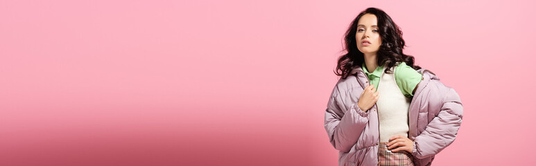 young woman in puffer jacket posing on pink background, banner