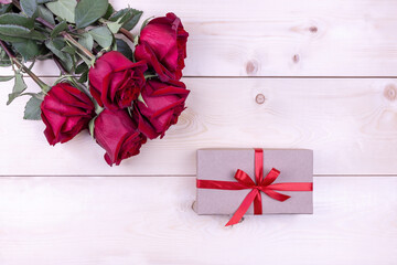 red roses and gift box on wooden background