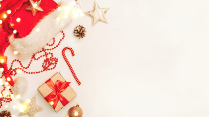 Christmas and New Year banner with copyspace. Festively decorated  Gift boxe, Santa Claus hat, cane lollypop, cones, christmas balls and stars on white wooden backdrop.
