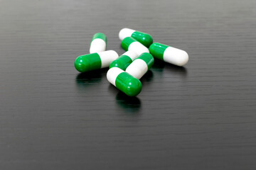 green and white medicine capsules on black background