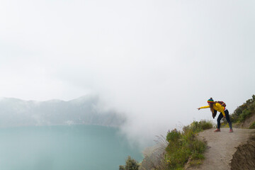 girl photographer jumping in spectacular landscape lagoon inside quilotoa volcano ecuador latin...