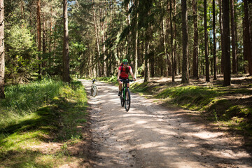 Obraz premium Young woman with helmet riding mountain bicycle in the forest.
