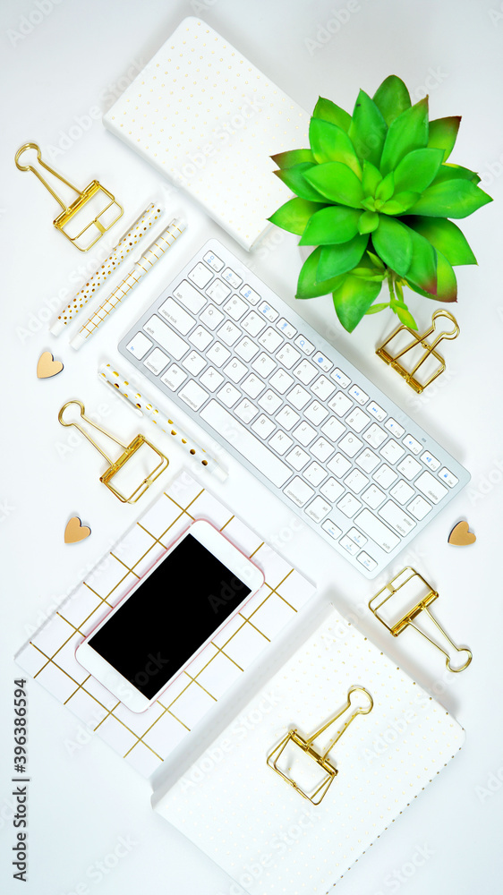 Wall mural stylish white and gold theme desktop workspace with keyboard, notebooks and smart phone. top view bl