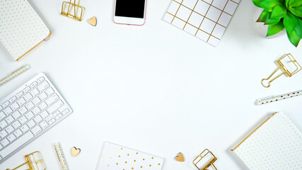 Stylish white and gold theme desktop workspace with keyboard, notebooks and smart phone. Top view...