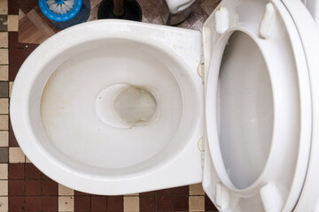 Dirty unhygienic toilet bowl with limescale stain at public restroom, top view