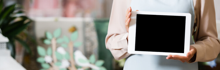 Cropped of female florist holding digital tablet with blank screen on blurred background, banner