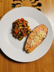  baked red fish with cheese with stewed vegetables on a large white plate