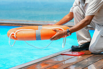 African man rescuer with lifebuoy in pool. African hotel worker throws a lifeline to man drowning...