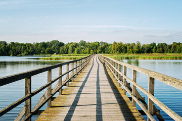 Obraz premium Rustic wooden bridge leading across a wide river.