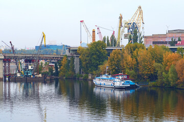 Close-up view process of unmounting  an old bridge to the Rybalskyi Island (or  Peninsula). Heavy cranes are used to dismantle bridge structures. Old crane booms in the background. Kyiv, Ukraine