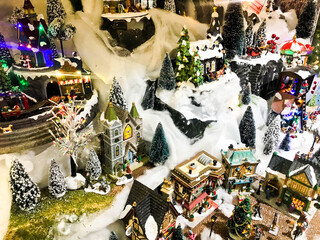 New Year's landscape. miniature for the showcase. toy people and houses, synthetic snow. Christmas trees in the yard, decorated with balls and garlands