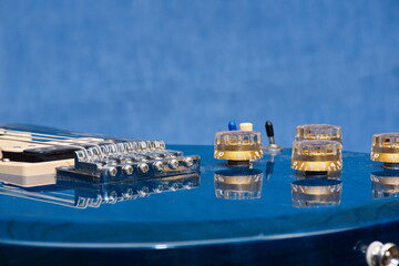 Close up of a vibrant blue electric guitar, with the controls reflected in the high-gloss finish on...
