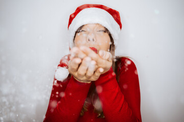 .Beautiful woman dressed as Mama Claus with a hat and a red sweater. About to blow snowflakes. Christmas time