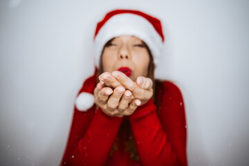 .Beautiful woman dressed as Mama Claus with a hat and a red sweater. About to blow snowflakes. Christmas time
