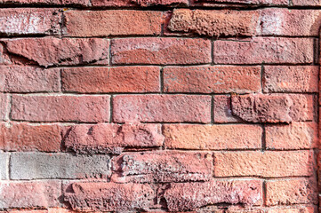 Stone wall patterned bricks, carved uneven imitation of a red brick wall, plaster. Texture.
