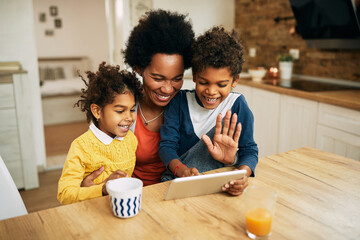 Happy black mother and her kids having video call over touchpad at home.