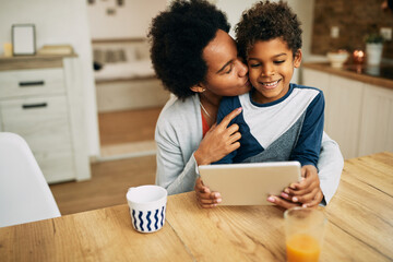 Loving African American mother and son using digital tablet at home.