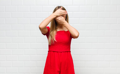 blonde woman covering face with both hands saying no to the camera! refusing pictures or forbidding...