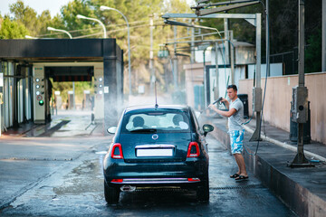 Manual car wash with water under pressure in a car wash on the street. Summer car wash. Cleaning the car with high pressure water. Washing with water