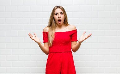 blonde woman feeling extremely shocked and surprised, anxious and panicking, with a stressed and...