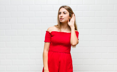 blonde woman looking serious and curious, listening, trying to hear a secret conversation or...