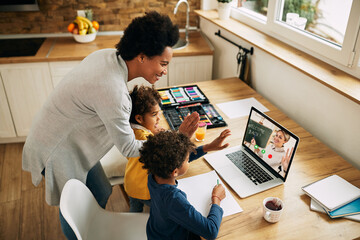 Happy African American family greeting a teacher during a video call over laptop.