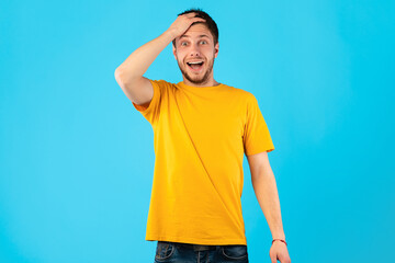Surprised guy with open mouth holding hand on his head