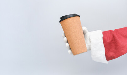 Christmas coffee. The Santa hand holding cup of cofee to go. takeaway coffee for holiday.copy space for text. The season, winter, holiday, celebration, gift concept.