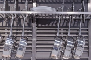 shiny pans hang on a hanger in the kitchen