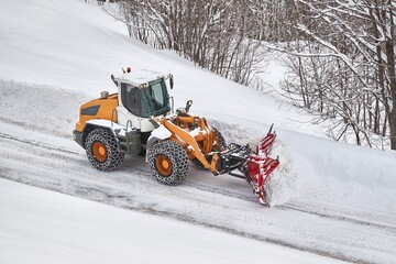 Snow plow machine clearing snow from roads after heavy snowfall in the Alps