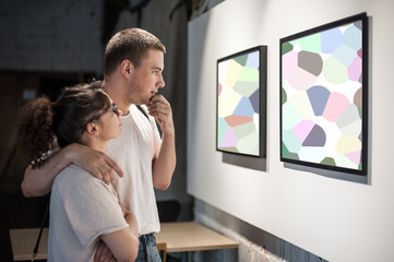 Young couple in modern art exhibition gallery hall contemplating artwork. Abstract painting