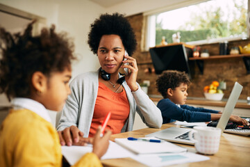 Black single mother talking on the phone while working at home.