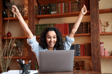 Excited young woman screaming yes using laptop
