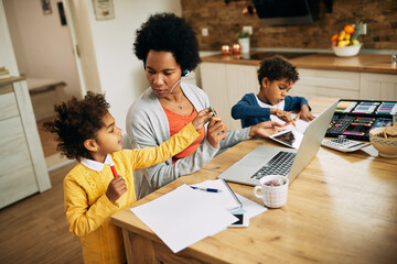 African American single mother with two kids working at home.