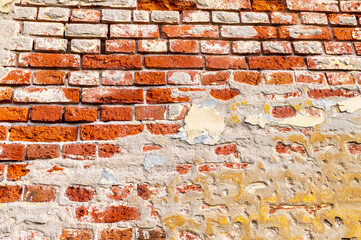 Old worn red brick wall with knocked down plaster, chipped, scratched with plaster, close-up, texture.