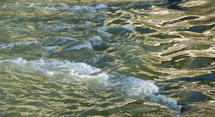 Rapid flow of the mountain river Sochi. Clear emerald water with waves and stone rapids.