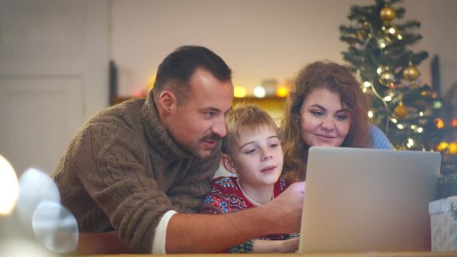 Happy mother, father and son doing online shopping for christmas gifts on laptop at home