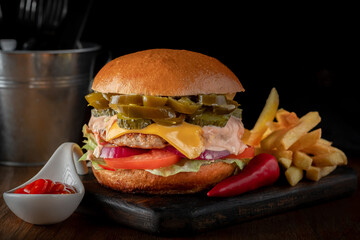 Bbq beef cheeseburger with pickled Jalapeno peppers, cheese and vegetables with French fries on the...