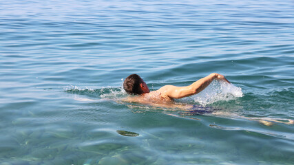 Muscular swimmer floats on the surface of the water, creating splashes