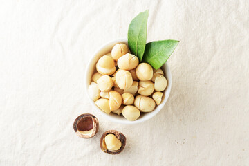 Macadamia nut in a white cup on a light fabric with a copy of space. Top view.