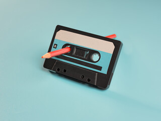 Fototapeta premium Vintage audio cassette and pencil on blue background